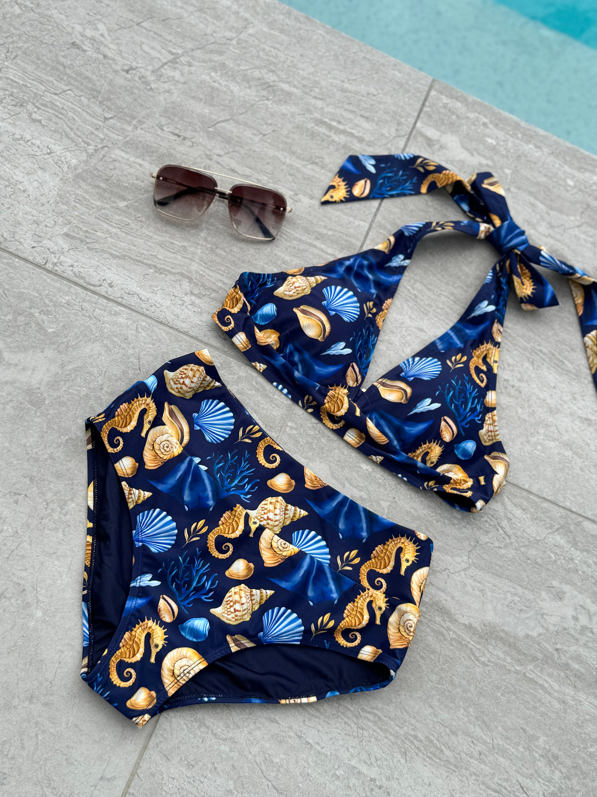 Čiovo navy seashell print halter bikini top and mid waist bottoms styled poolside with sunglasses