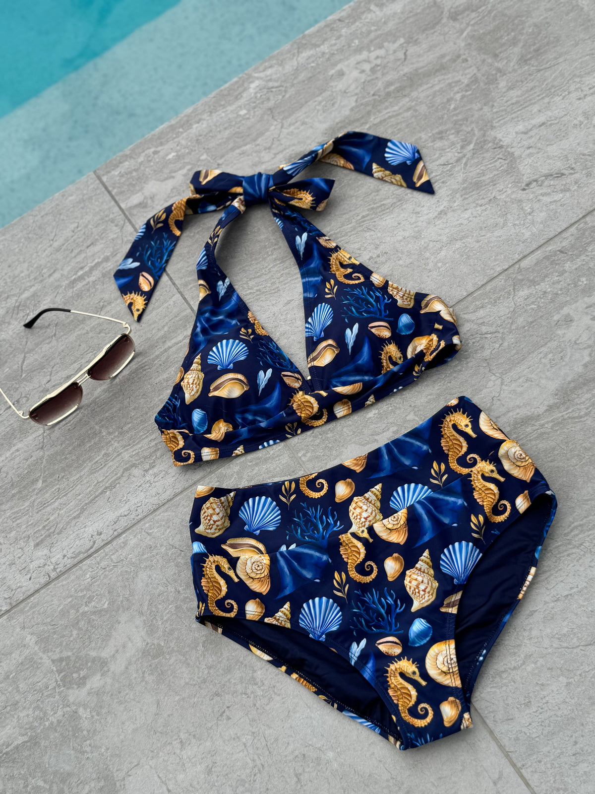 Čiovo navy seahorse print bikini styled poolside with sunglasses on a crochet cushion